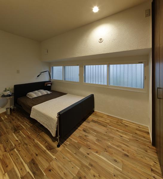 LDKと緩く繋がった間仕切りナシの隠れ家的な寝室です。開口部からLDKの広いスペースが見えないようカギ状の入室動線を造りました。節目の美しいアカシア無垢材を床に 珪藻土を壁に施工。インナーサッシで断熱性もアップ！