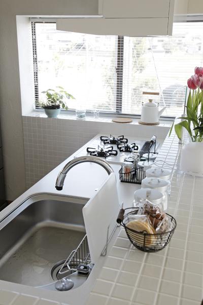 エレガンスな白いキッチンです。配置に悩んでたどり着いた「収納力と見晴らし」を兼ね具えるご自慢のスポット。窓からの光が白タイルに反射して明るい室内に。カウンターは弊社の施工事例をヒントにリクエストされた造作品です。