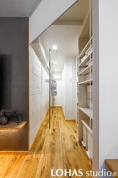 キッチンの横には回遊できるユーティリティースペースを。パントリーも兼ねているので、食品ストックも、備品も、掃除用具も全てここにひとまとめ。更に、ハンパだった縦長の空間は室内干しスペースに有効利用。湿気を取るエコカラットをアクセントにし、換気扇もあるので雨の日でもバッチリ！