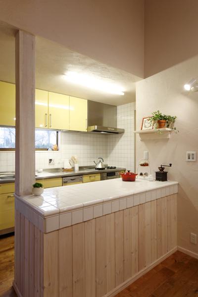 奥さまお好みのレモン色を採用した明るいキッチンです。カウンターは構造柱を上手に組み込んでパイン材とタイルで造作しました。内側を使い収納を十分にご用意し家族分の食器やキッチン雑貨をすっきり収めました。