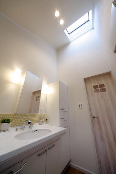 レイアウトを変更して造作した明るい洗面室です。場所を変えたことでトップライトが入るように。バルコニーにも近く洗濯時の家事動線が改善しました。湿気に強く踏み心地の柔らかさが特徴のコルク材を床敷設。室内デザインに合わせて扉を造作しました。