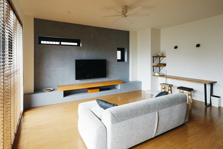 LDKで目を惹くテレビ背面のモルタル風の壁は、「コンティニューオ」という耐久性・耐水性のある塗り壁素材を採用し、グレーの壁が映えるリビングに。