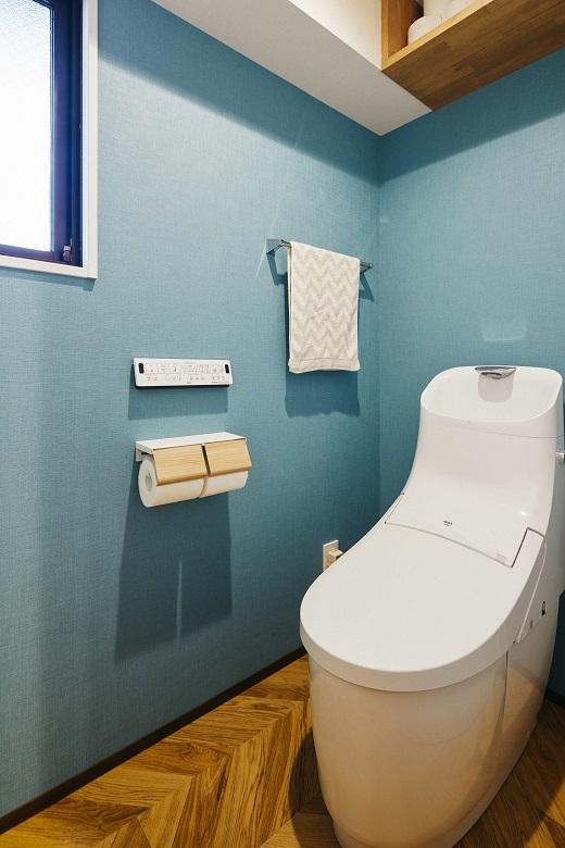 青い壁とヘリンボーン張りの床でトイレもお洒落。