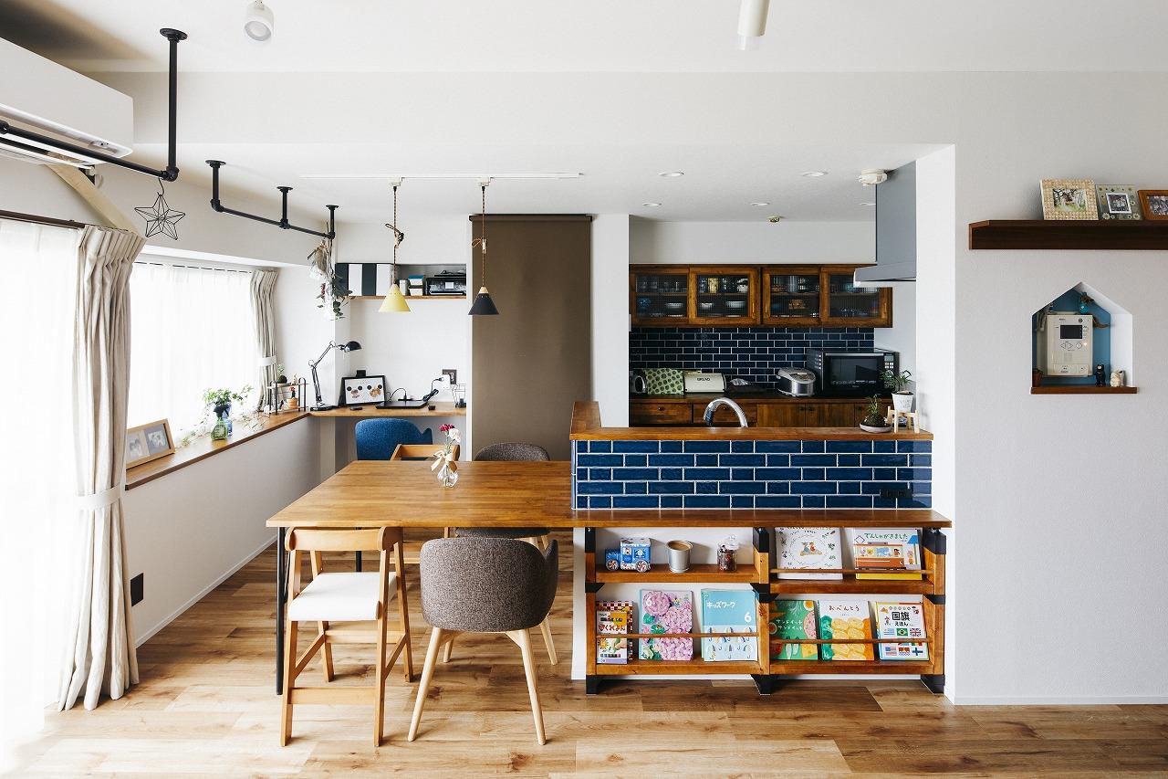 キッチンはダイニングテーブル一体型。キッチンの背面収納とダイニングテーブルの色味を合わせ、青いタイルをアクセントにしています。