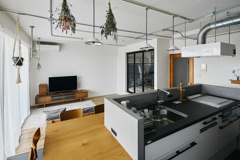 キッチンの腰壁には水にも強いコンティニューオという素材を採用。シンプルな色味でありながらも、モルタル調の無機質な質感が優しい木の色のダイニングテーブルと調和します。