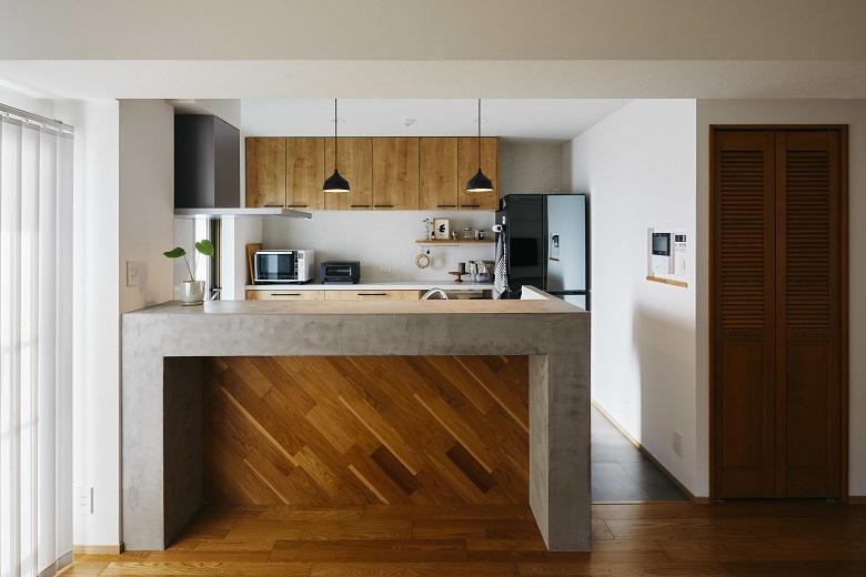 キッチンの腰壁にはモールテックスを採用。木の雰囲気をより目立たせるため斜めに木材を貼り、空間のアクセントに。