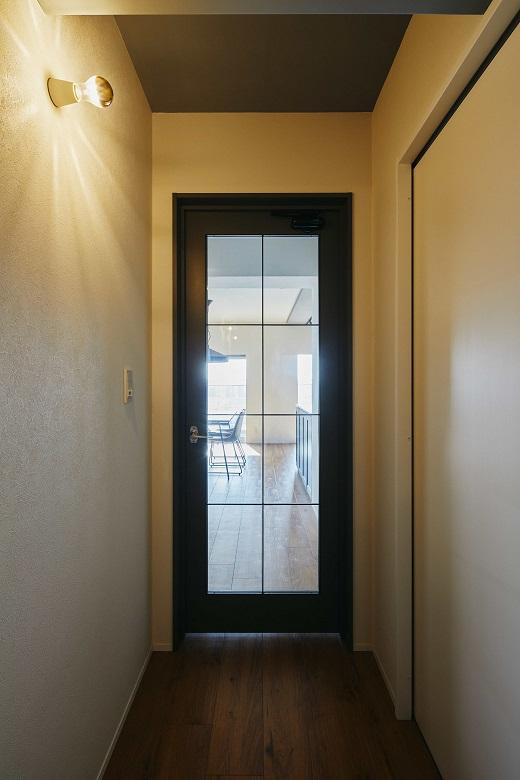 リビング建具とブラケットライトの創り出す陰影で、印象的な廊下に。