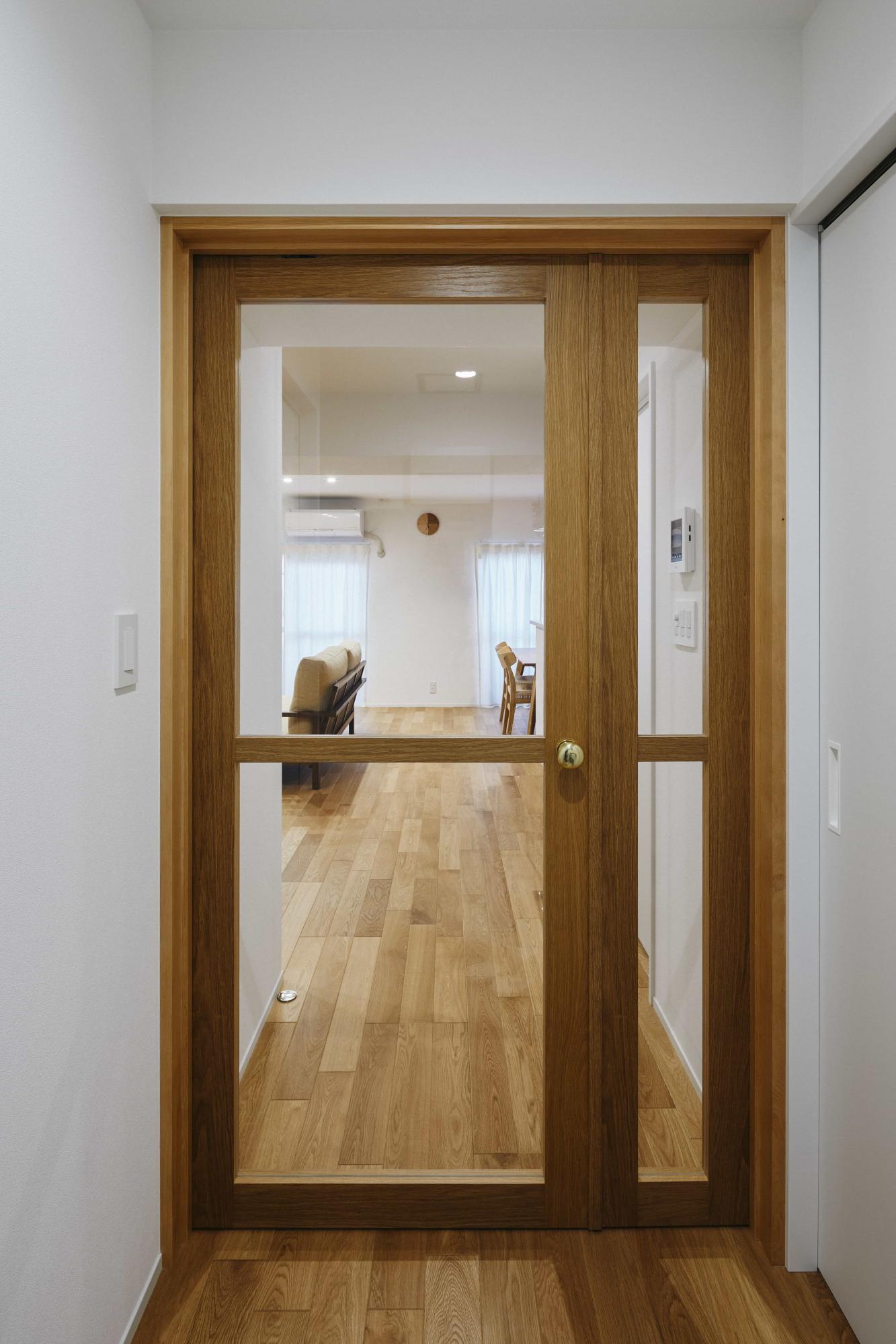 廊下からリビングに繋がる建具は、両側開閉できる親子扉で造作。ガラスの面積を増やし、空間の広がりや光をたくさん取り入れられるように工夫が施されています。