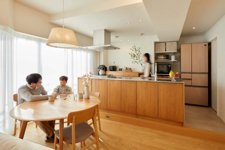 マンションの配管移設によって生じる段差を逆手にとって、キッチンの床全体を一段上げたステージのような空間を実現。床色を変えることでよりキッチンの木目が映えるようなデザインにしています。