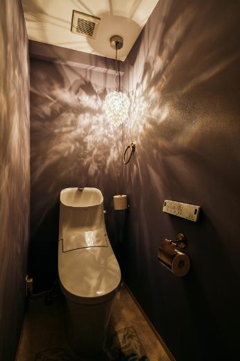 ラベンダー色のクロスやアンティークゴールドのアクセサリーが可愛らしいトイレ空間。スワロフスキーのペンダントライト一灯のみの照明計画で、幻想的な雰囲気を演出しています。