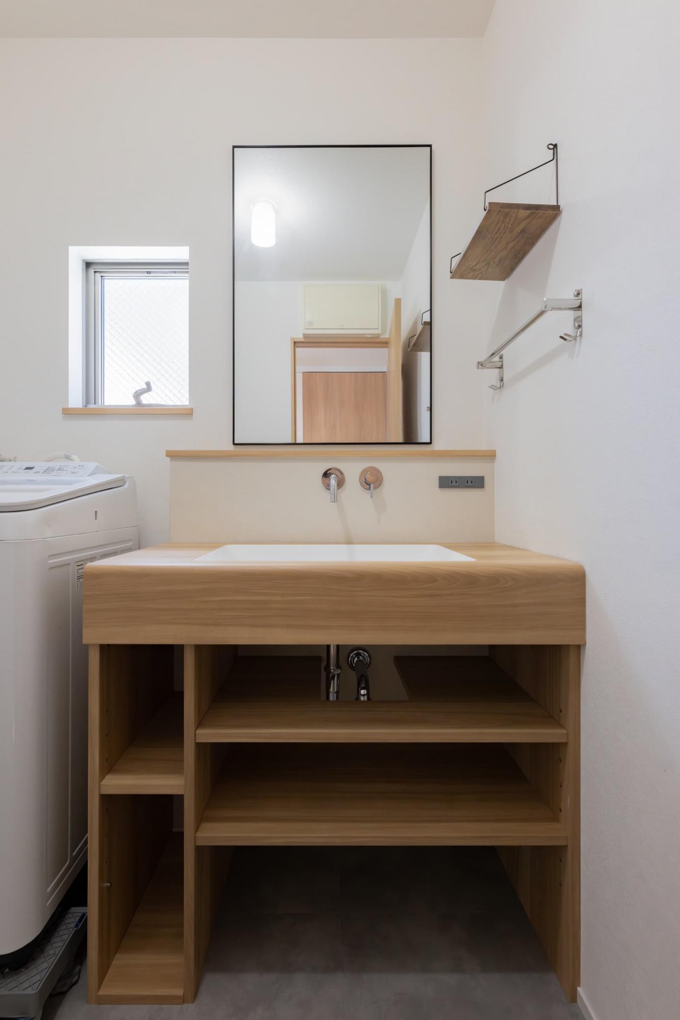 造作洗面台は温かみのある木目調のメラミン材で製作。背面のクロスはアクセントとし、洗面台がより映えるように計画しました。