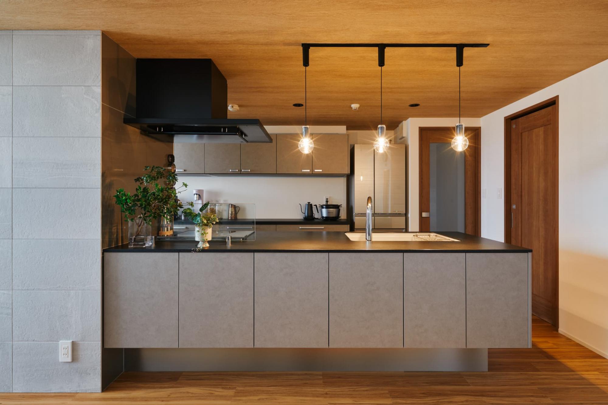 敢えてリビングとキッチンで床材を貼り分けず、ダークカラーのキッチンが美しい木目によってより映えるデザインとしました。
