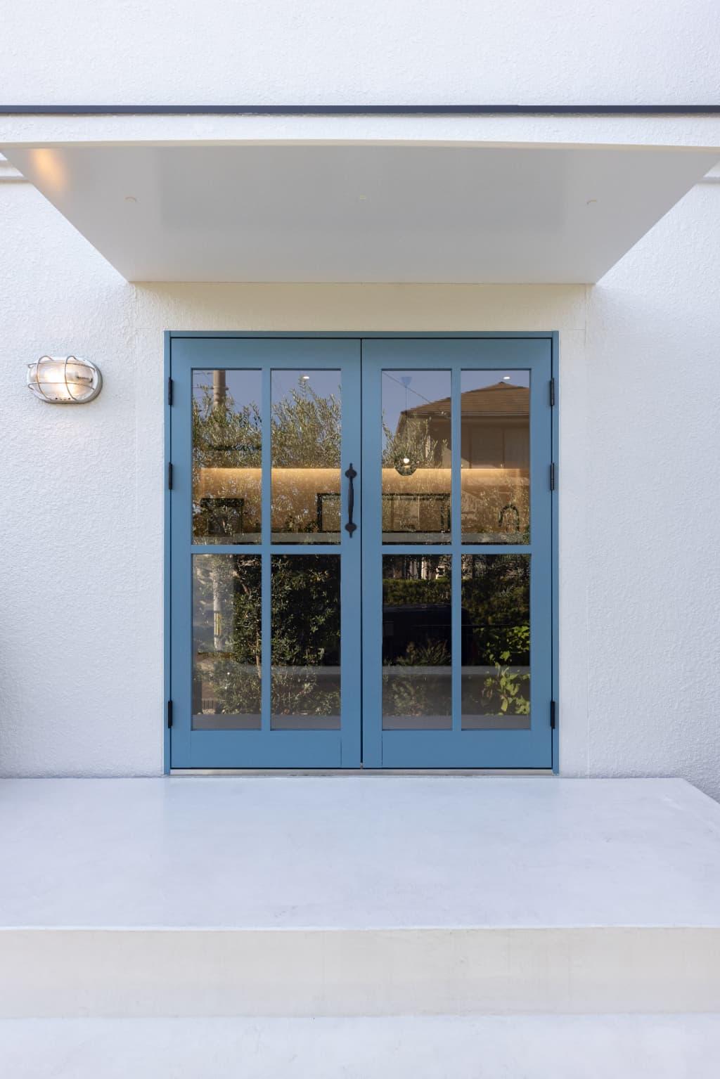 グレーだった外壁も白色で塗装。ポーチも白の階段で計画し、扉の水色が映えるデザインにしています。