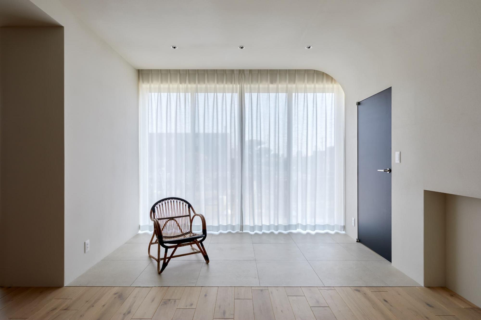 床を大判の陶磁器タイルで仕上げた縁側スペース。天井まで届くハイサッシからたっぷりの光が降り注ぎ、庭の景色を一望できます。