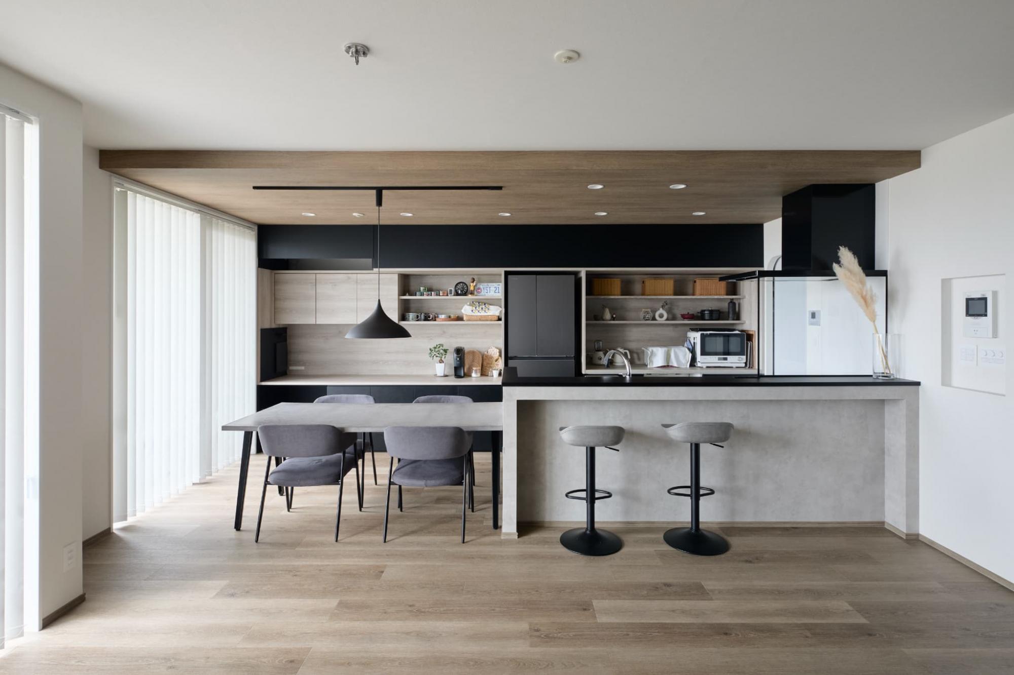 造作カップボードはブラックを基調とし、キッチンの腰壁にはモルタル調の壁紙を取り入れています。