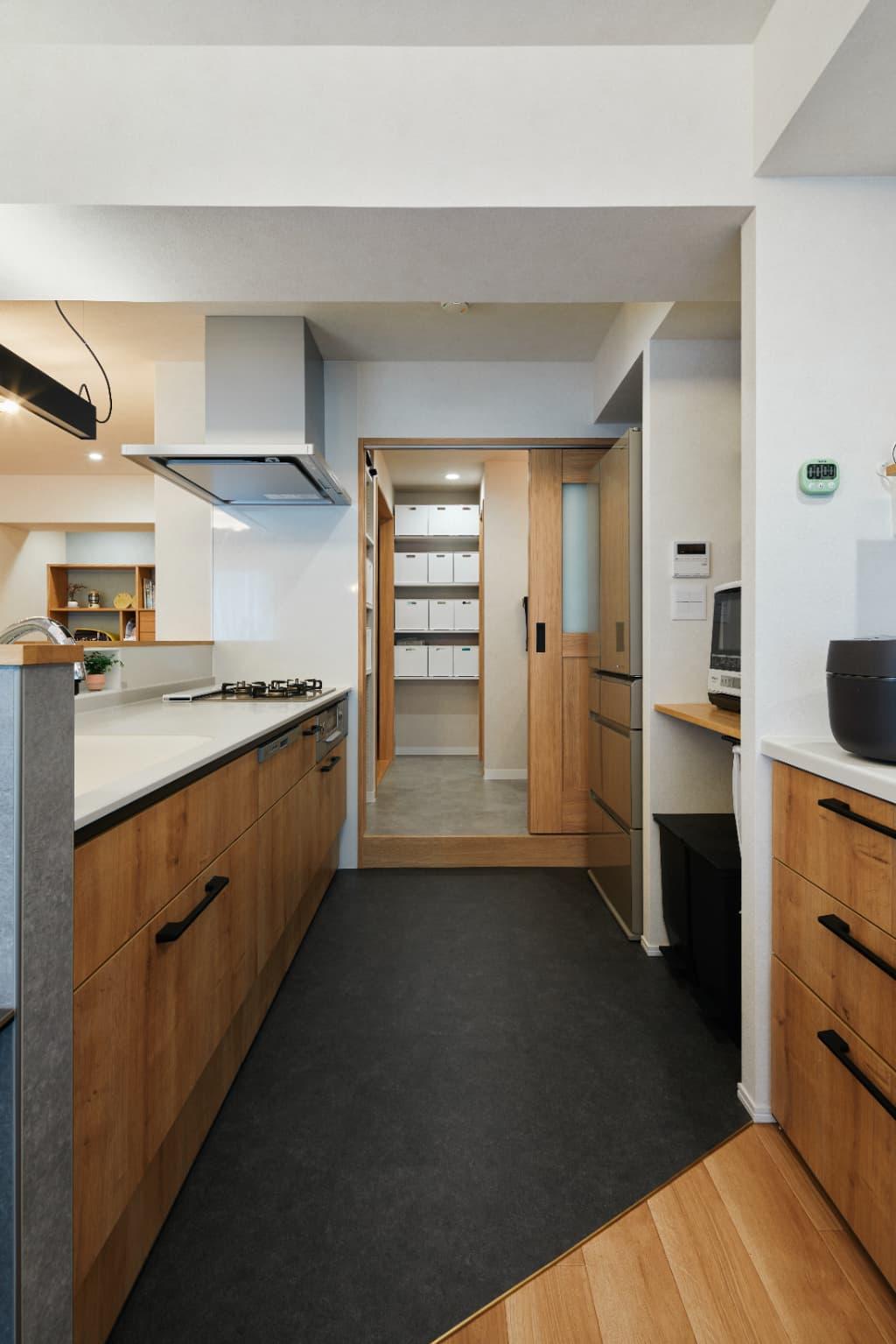 キッチンの足元はフロアタイルにして、清掃性と意匠性をアップ。段差が強調しないように、建具下に同材の無目枠をまわして空間に馴染ませています。