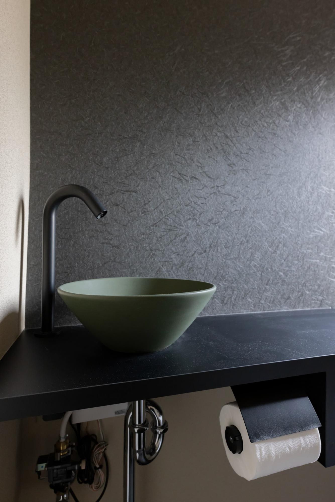 造作手洗いカウンターを設置。黒のアクセントクロスや緑の洗面ボウルで、落ち着いた和モダンな雰囲気を感じられます。