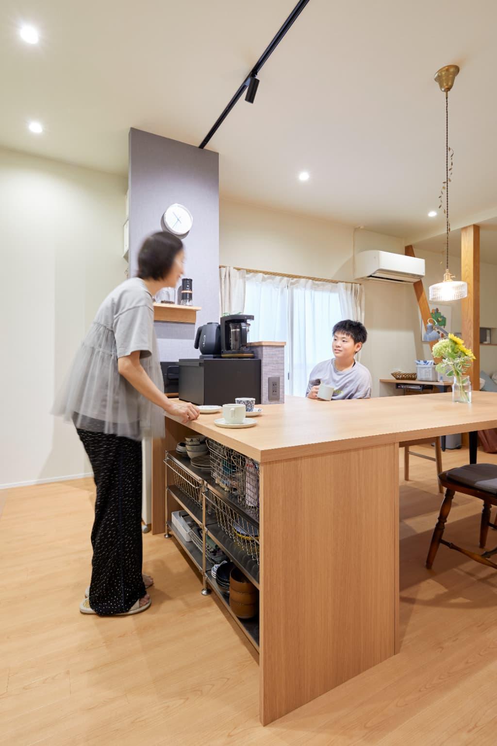 天板が繋がることで開放感を出しつつも、スムーズな配膳が可能に。キッチン側の収納部分は無印のステンレスフレーム収納がシンデレラフィットするように計画。