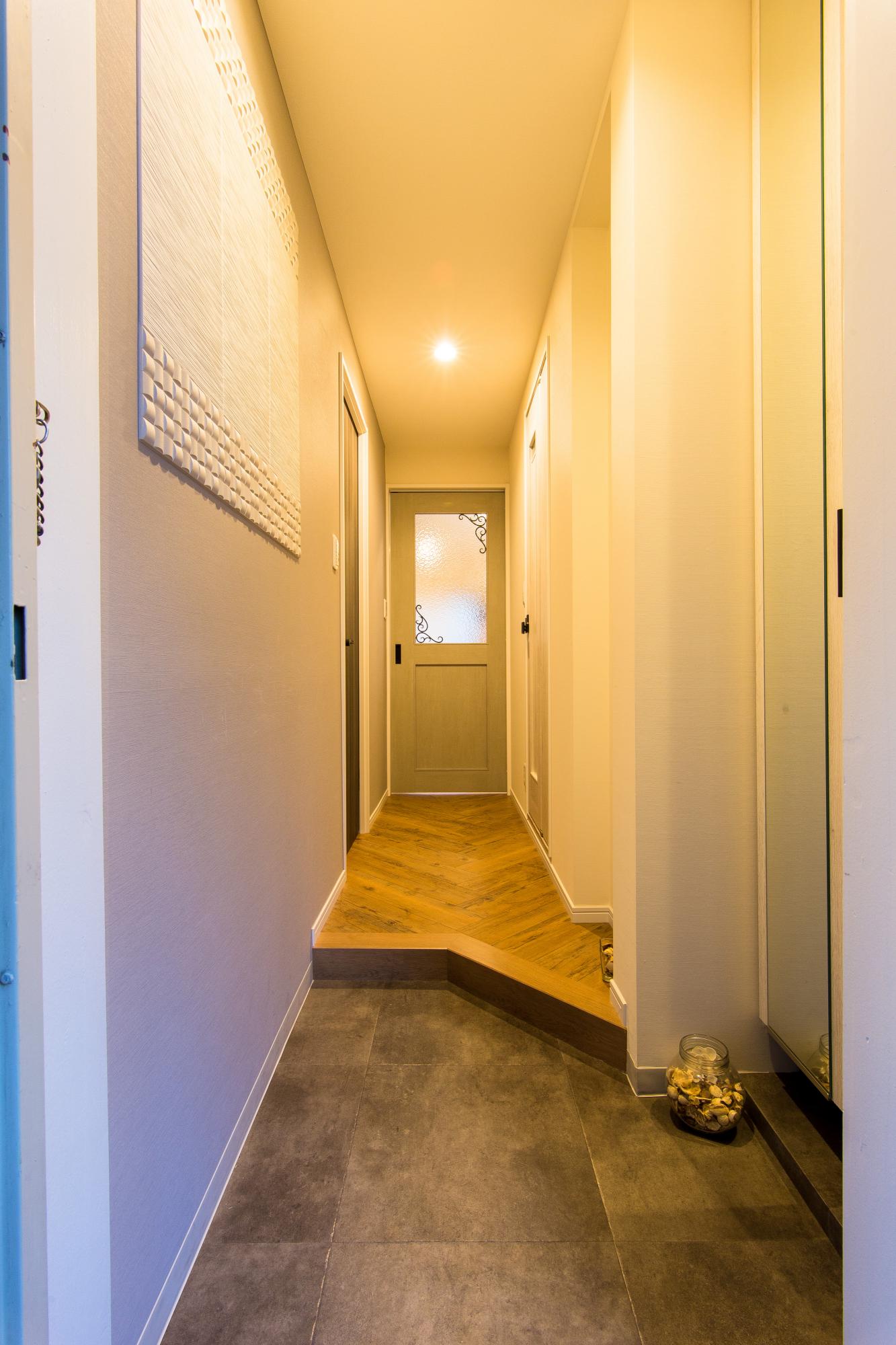 帰ってきてほっとできる空間にするため、玄関の框は斜めにカットし 正面の扉にもこだわることで、奥行き感と期待感を強調しました。