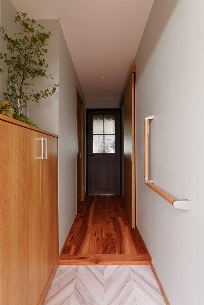 ヘリンボーンの玄関土間にはシンプルな内装でグリーンも映えます。
正面はインテリアを引き締める色＆ニュアンスある室内ドアを選びました。
手摺もつけて安全にも配慮しています。