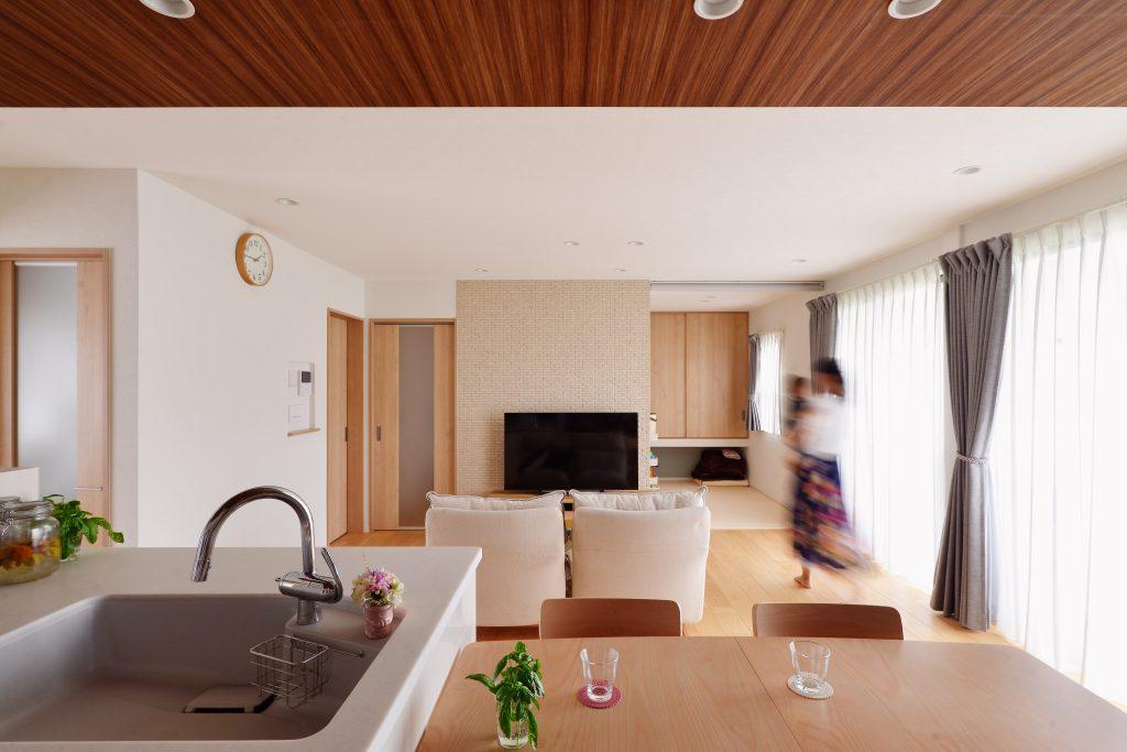 対面キッチンから望むリビング。正面右側にキッチンからも様子を確認できるキッズスペースを設けました。