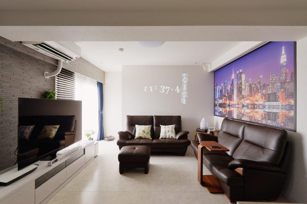 シーリング一体型のプロジェクター「アラジン」で映し出した時計。スポーツ観戦も映画鑑賞も大迫力です。外に面する壁はエコカラットを貼りました。調湿機能はもちろんお部屋のアクセントにもなっています。