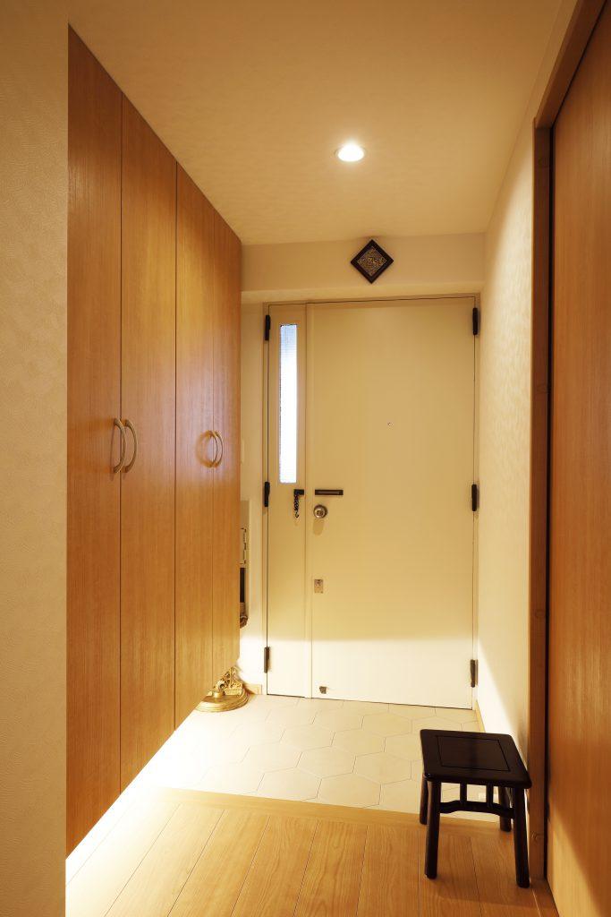 狭かった玄関はゆったり靴の脱ぎ着ができる明るい空間へ。下部を浮かした収納は圧迫感の軽減と照明を組み込んで高級感も演出。