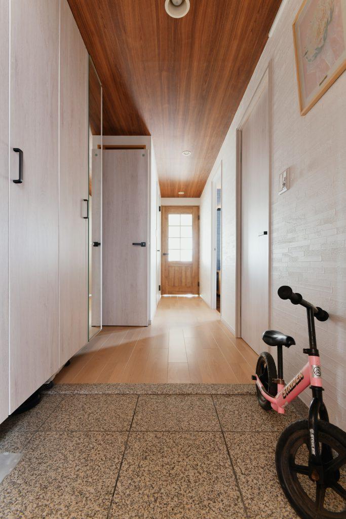 廊下の天井に木目のアクセント。建具は白に統一して広がり感を演出。