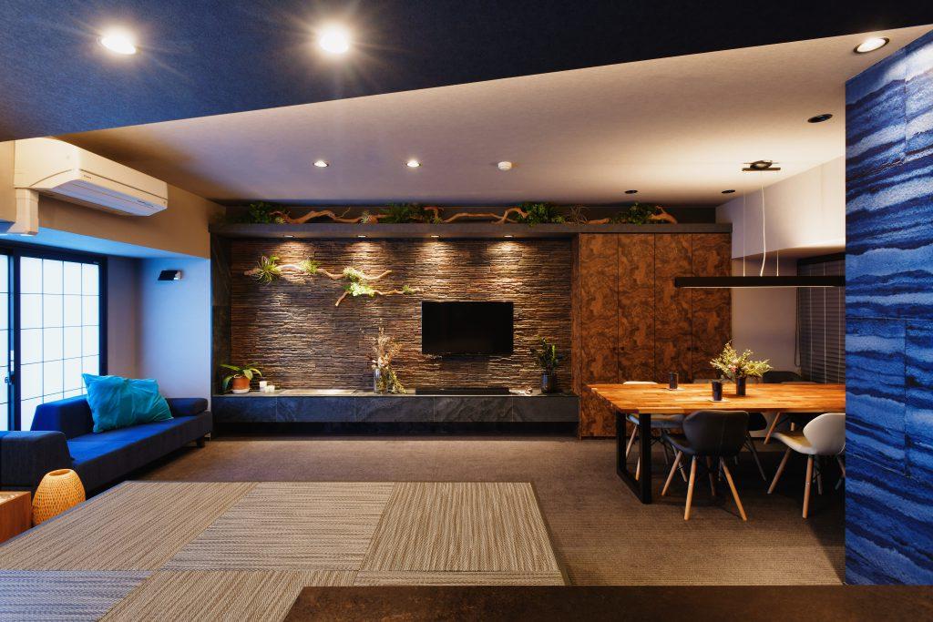 記憶に残る故郷を思いおこす岩肌や流木をインテリアで表しました。写真正面の壁右は仕事関係の書類をしまうトール収納。扉面材は杢柄にして木立をイメージしています。ローボードの左側にはバイオエタノール暖炉を埋め込んで、夜は火の揺らぎがくつろぎを感じさせてくれます。