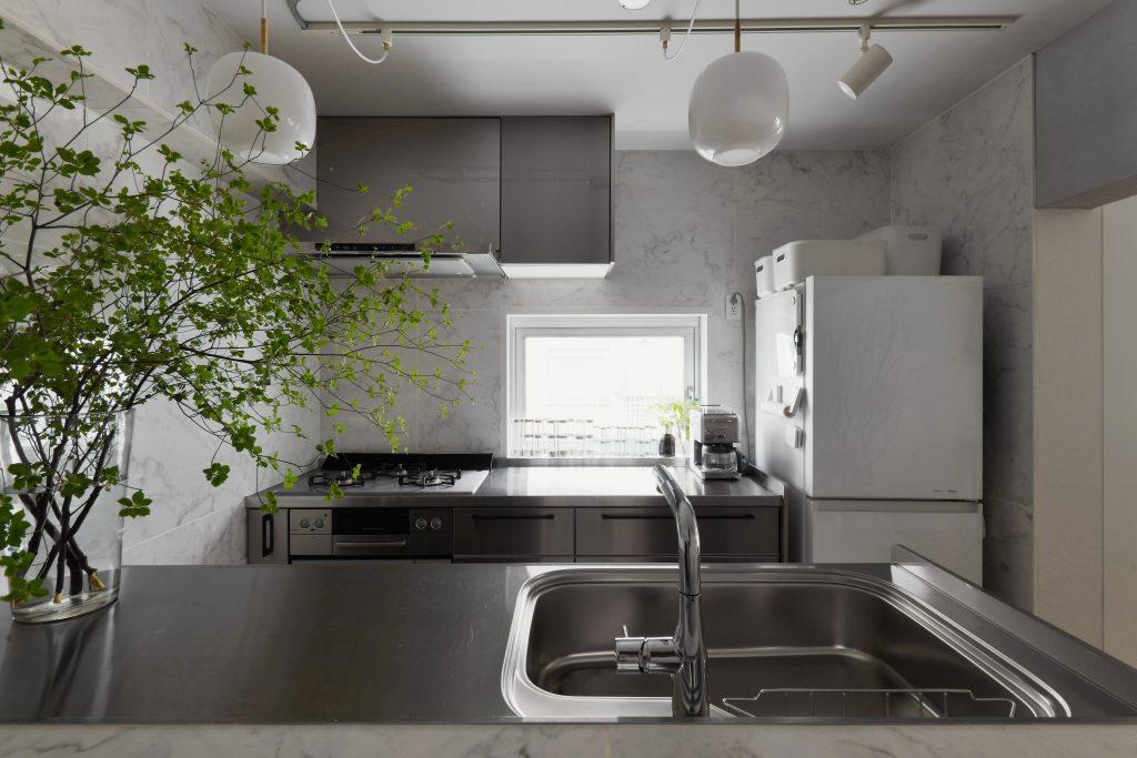 ステンレスキッチンとタイル仕上げの壁で雰囲気のある空間に。