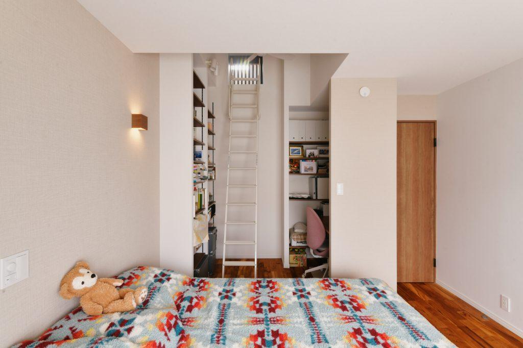 寝室には天井裏のスペースを有効活用したロフト収納を設けました。ハシゴの隣は高さを生かした本棚。