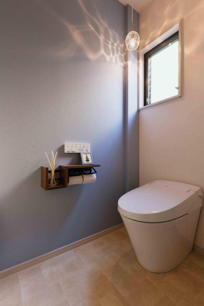 淡いブルーのアクセントクロスで清潔感もあるトイレ。実は階段下収納から出入りできるレイアウトになっていますが、階段下収納は扉のないアーチ形の開口になっているので違和感は全くありません。むしろお洒落です。空間の有効利用のお手本です。