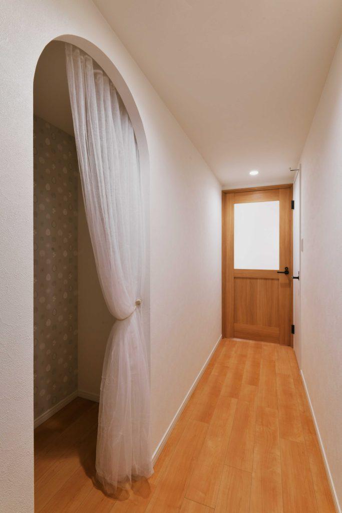 廊下に設けた収納はアーチ型の開口にして可愛らしく。内部にもアクセントクロスを貼りました。収納以外にもいろいろ使える+αの空間になりました