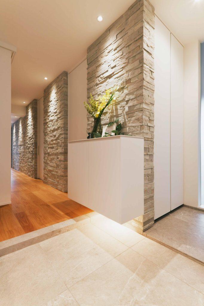 玄関からLDKへとつづく天然石の壁が空間にリズムを作っています。ダウンライトで石を照らすことで陰影が美しく浮かび上がります。