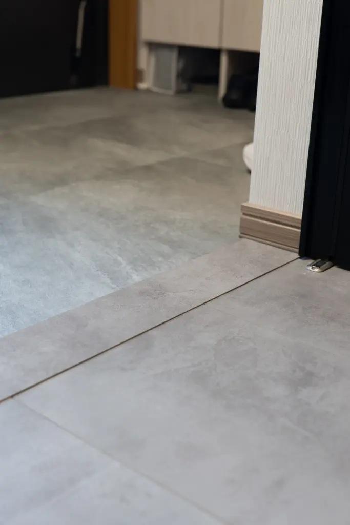 一見同じに見える床は、土間部分はモルタル調のフロアタイル、プラスαのスペースはフローリング仕上げです。壁に合わせてクロスも淡いグレーにして統一感を演出。