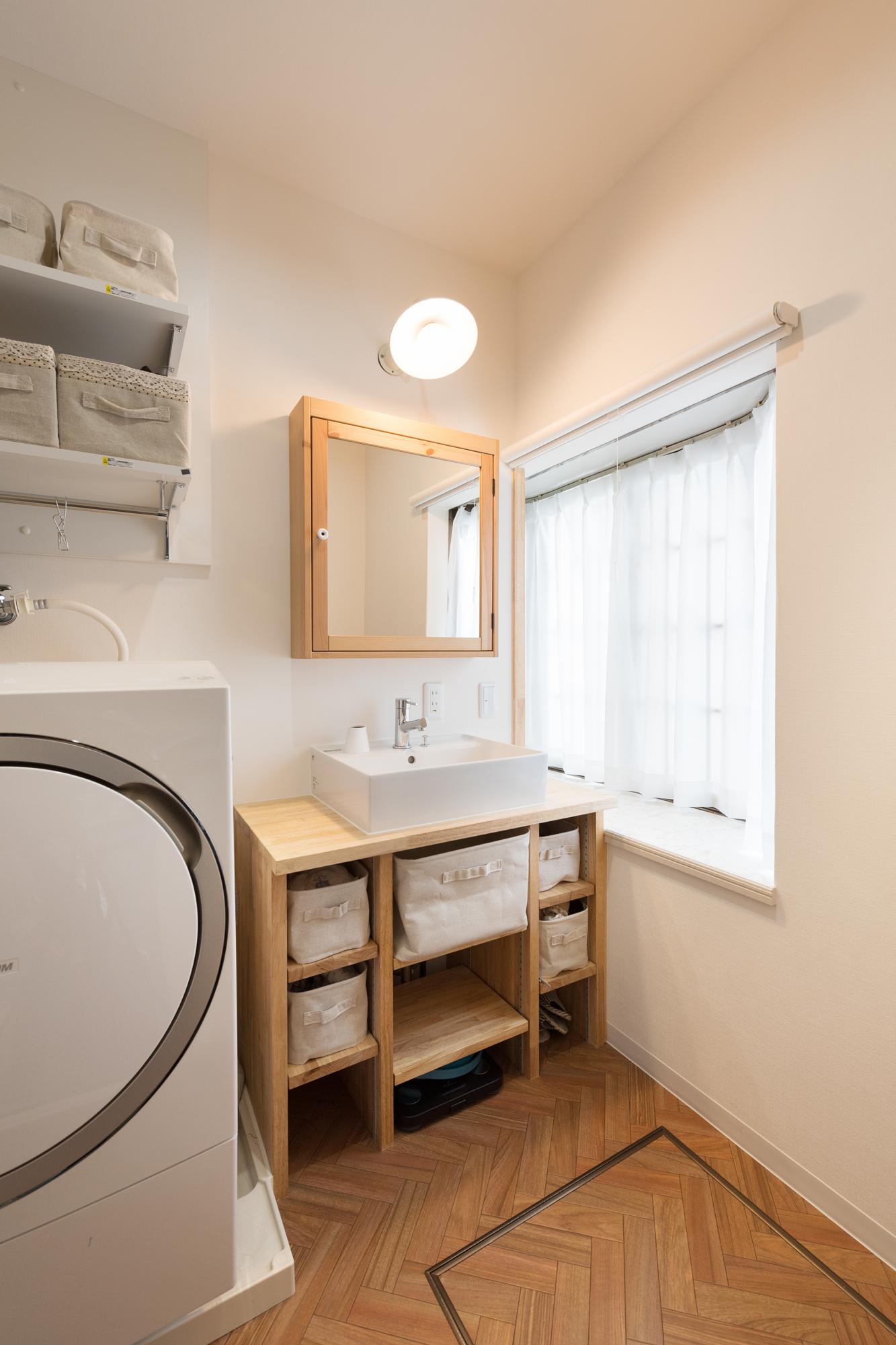 洗面台は造作し、ナチュラルデザインで統一。木の色、白壁、床はヘリンボーン貼り風のフロア材を選ぶなど、カフェのような素敵空間が完成。収納もたっぷり造り付けた