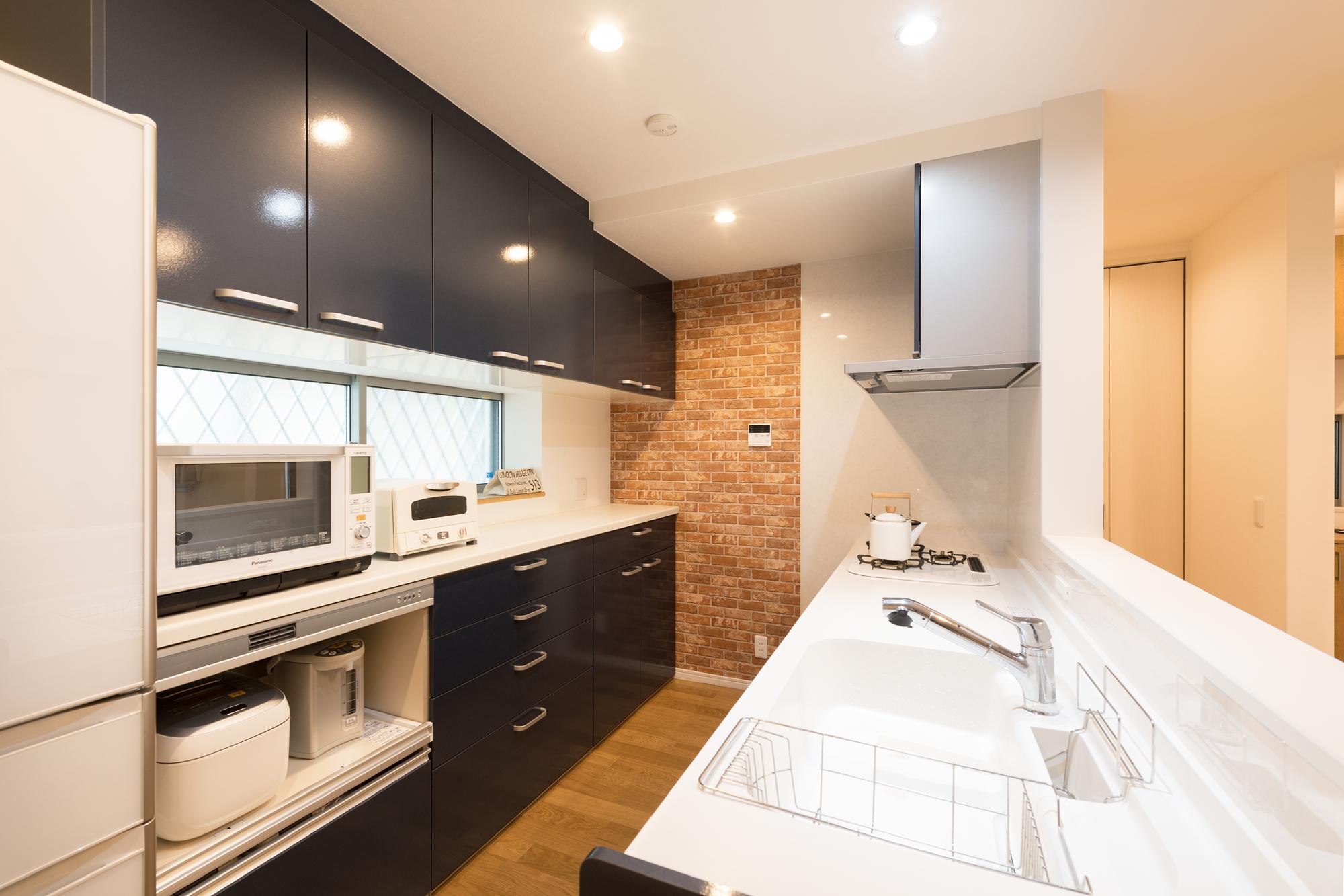 木のフローリングに、壁は白を基調にした柄クロスを貼り分けて。キッチンは引き締め効果のあるネイビーを選択。甘くなり過ぎないカッコイイ系のナチュラルデザインで統一