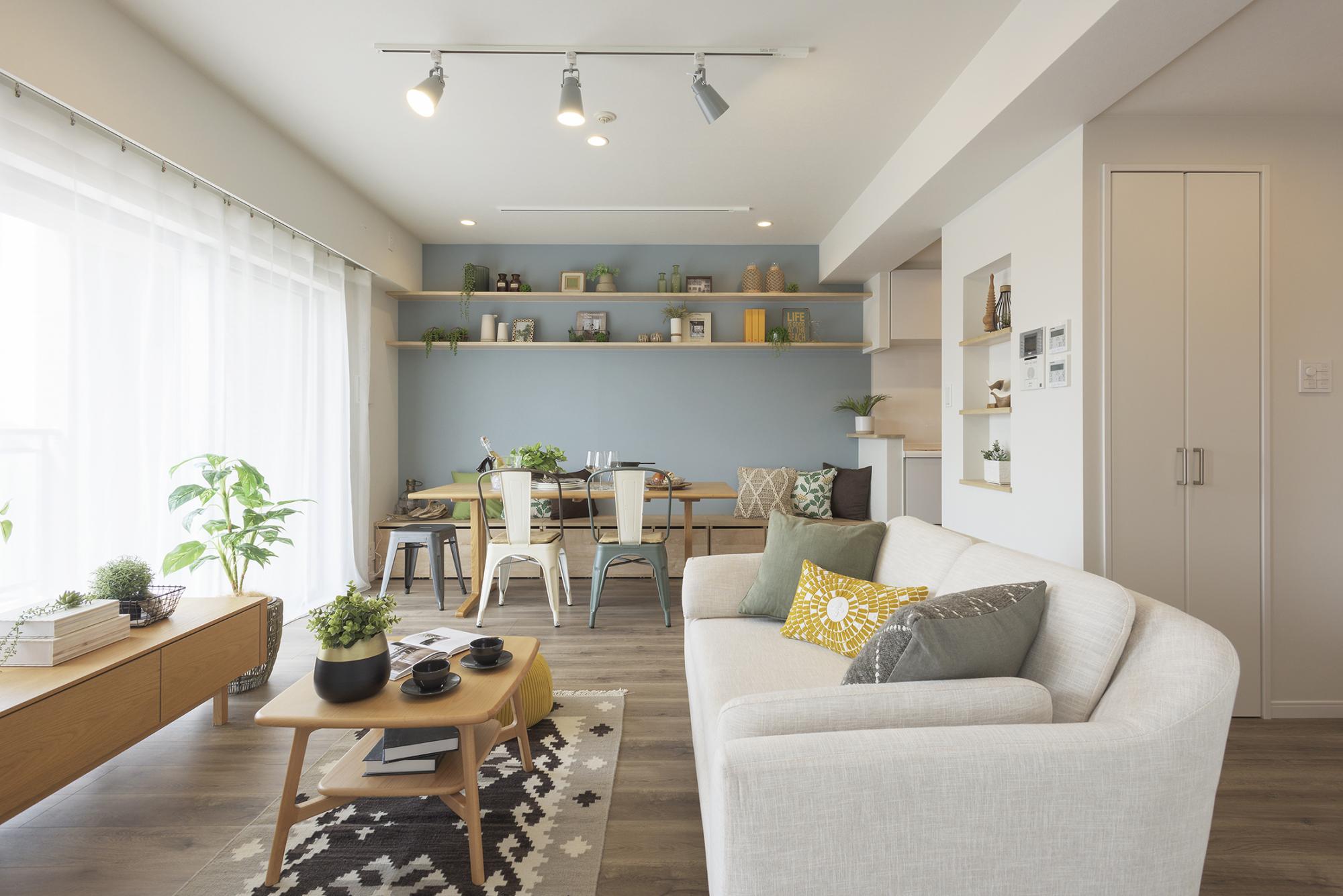 白と木目を基調とする中にブルーのアクセントクロスが映えるリビングダイニング。