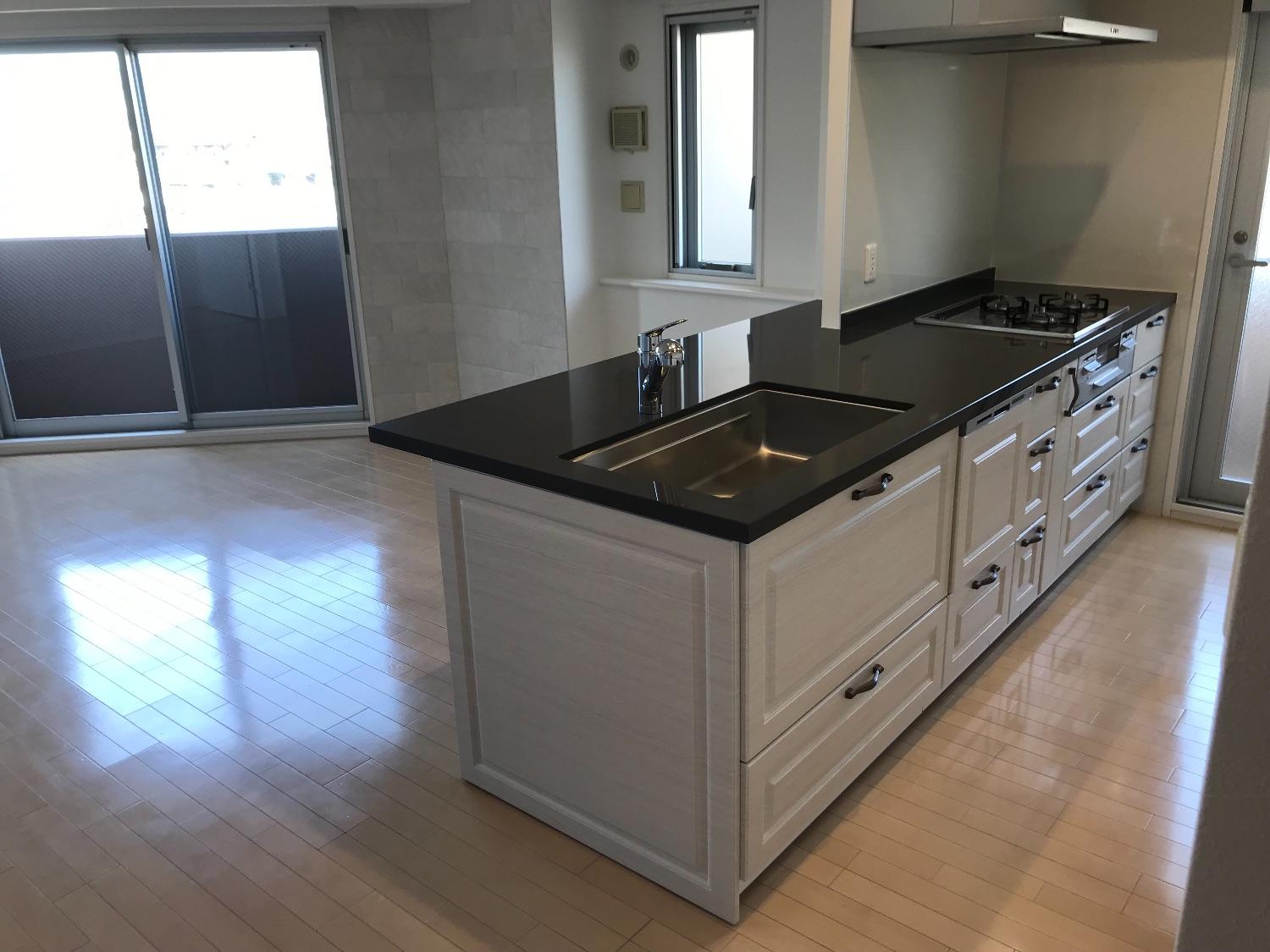 「高級感あるクオーツストーンのグレー天板のキッチンとブルーグレーの明るいお部屋」のキッチン