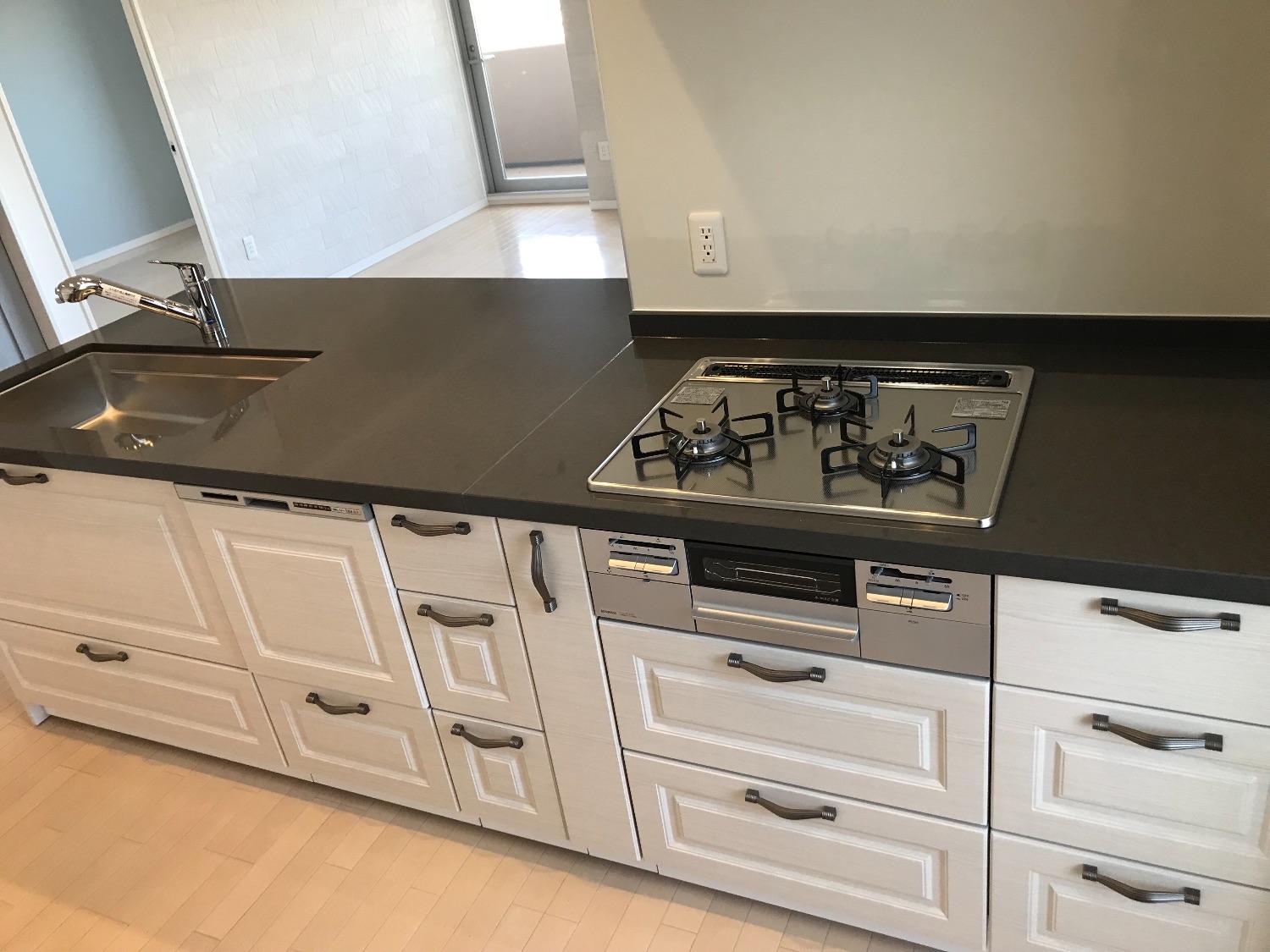 「高級感あるクオーツストーンのグレー天板のキッチンとブルーグレーの明るいお部屋」のキッチン