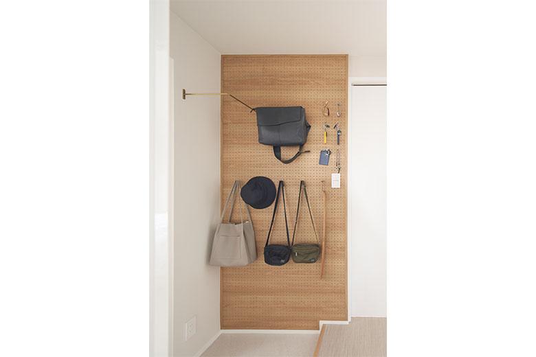 玄関の壁にはバックや帽子、小物がかけられる有孔ボードを。コートをかけられるアイアンバーも上部に配置した。