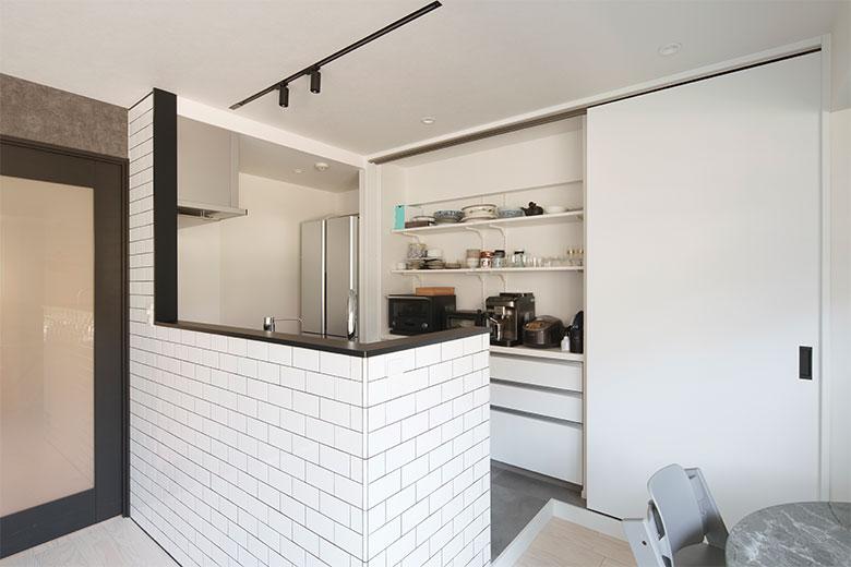 リノベテーマは「生活感のあるものを隠せるようにすること」キッチン背面に大容量の収納を配置。ここには食料品や家電や食器などのキッチン周りのものだけでなく、リビングダイニングで使うものも収納している。物がたっぷり入り、使いやすく、引き戸を閉めれば一気にすっきりとした空間に変わるのがうれしい。