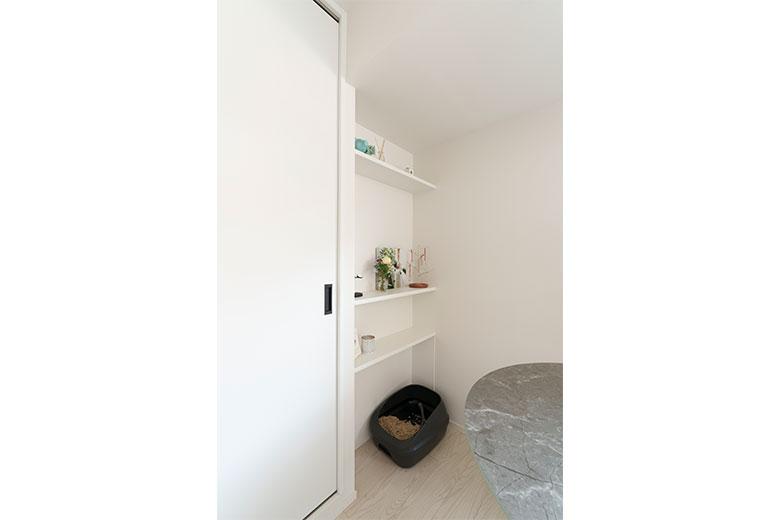 ダイニング奥のオープン棚収納の下は、愛猫のトイレ置き場。愛猫はトイレ後に壁を引っかくクセがあるそうで、以前の住まいではクロスをボロボロにしてしまったそう。リノベーション後は、トイレ置き場の壁だけキッチンパネルを貼って、カリカリしても傷がつきにくい対策を施した。