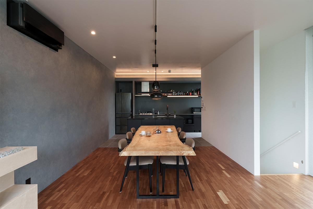 ホームパーティをして家族や友人を招くので、広く開放的なLDKはマスト。グレー系の塗装をしたアクセントウォール、間接照明、ブラック系のキッチンやペンダント照明と、一枚板のダイニングテーブルが調和して落ち着ける。