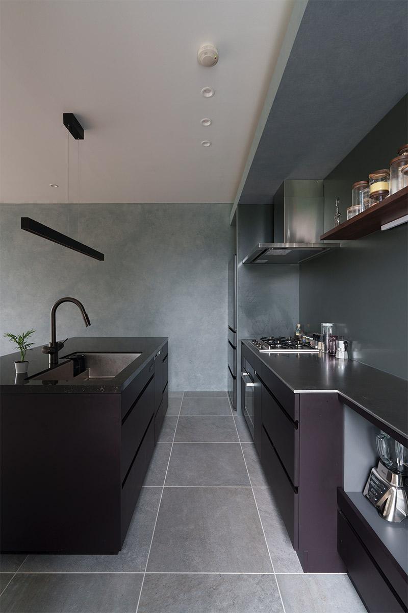 キッチンはオープンなⅡ型キッチンに。アメリカの家庭料理には必須だというオーブンをいれたコンロ側を壁付けにして、天板は熱い鍋も置けるステンレスを採用。シンク側は盛り付けや皿洗い中心なので、重厚感のあるクオーツ素材に。床材は手入れのしやすさを考えてグレーのフロアタイルを採用した。