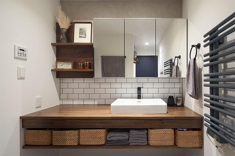 マットブラックの水栓とサブウェイタイルが目を引く洗面台は、ひとめ惚れした事例から採用した。洗顔の時に水が飛ぶので洗面ボウルを大きくしたとか。タオルウォーマーは海外のリノベーション番組を見て採用したもの。洗面室がほんのり暖かくなるのもうれしい効果だったそう。