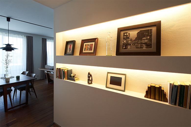 以前から集めていた絵画や本を飾るニッチを廊下に設けてはと、建築士から提案された。間接照明を入れ、背面にラフな塗装風テクスチャーのクロスで演出した２段のニッチは、高さを持っている絵の大きさに合わせ、本も置けるように奥行きを調整したのでぴったり。