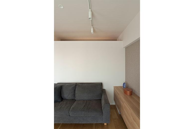 リビングとWICの間仕切り壁は、収納内の換気が心配で上部を開口することに。WIC内の照明がリビング側から見ると間接照明のように灯る。これは、WICの天井に梁があることを逆手にとって美しく仕上げたら…と建築士からの提案だったとか。