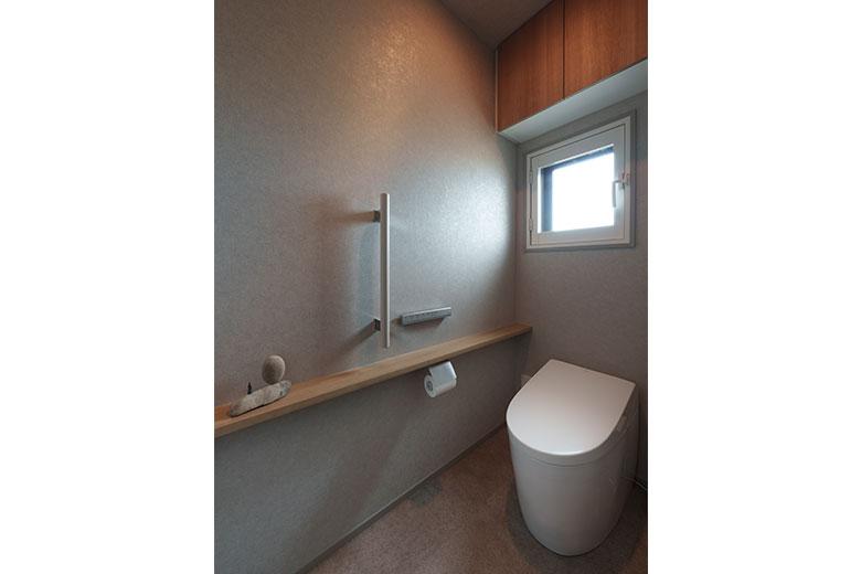 トイレは一段深い色でゆったり過ごせる空間に。引き戸にしたが洗面室内にあるので、静かでおこもり感があって音やにおいも気にならない。トイレをはじめ、洗面室やキッチンの水周りの床はフロアタイルにした。