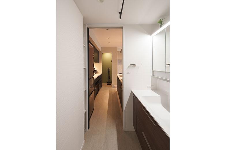 洗濯機のある洗面室と、キッチンがつながって家事動線が抜群に。水周りの設備を新しくしようとは考えていたが、キッチンとつなげることは思っていなかったので、うれしい提案だったと話す。洗面室の風通しが良くなり、湿気がこもらないのもうれしいという。正面に見えるパントリーまで、家事動線が一直線につながる。